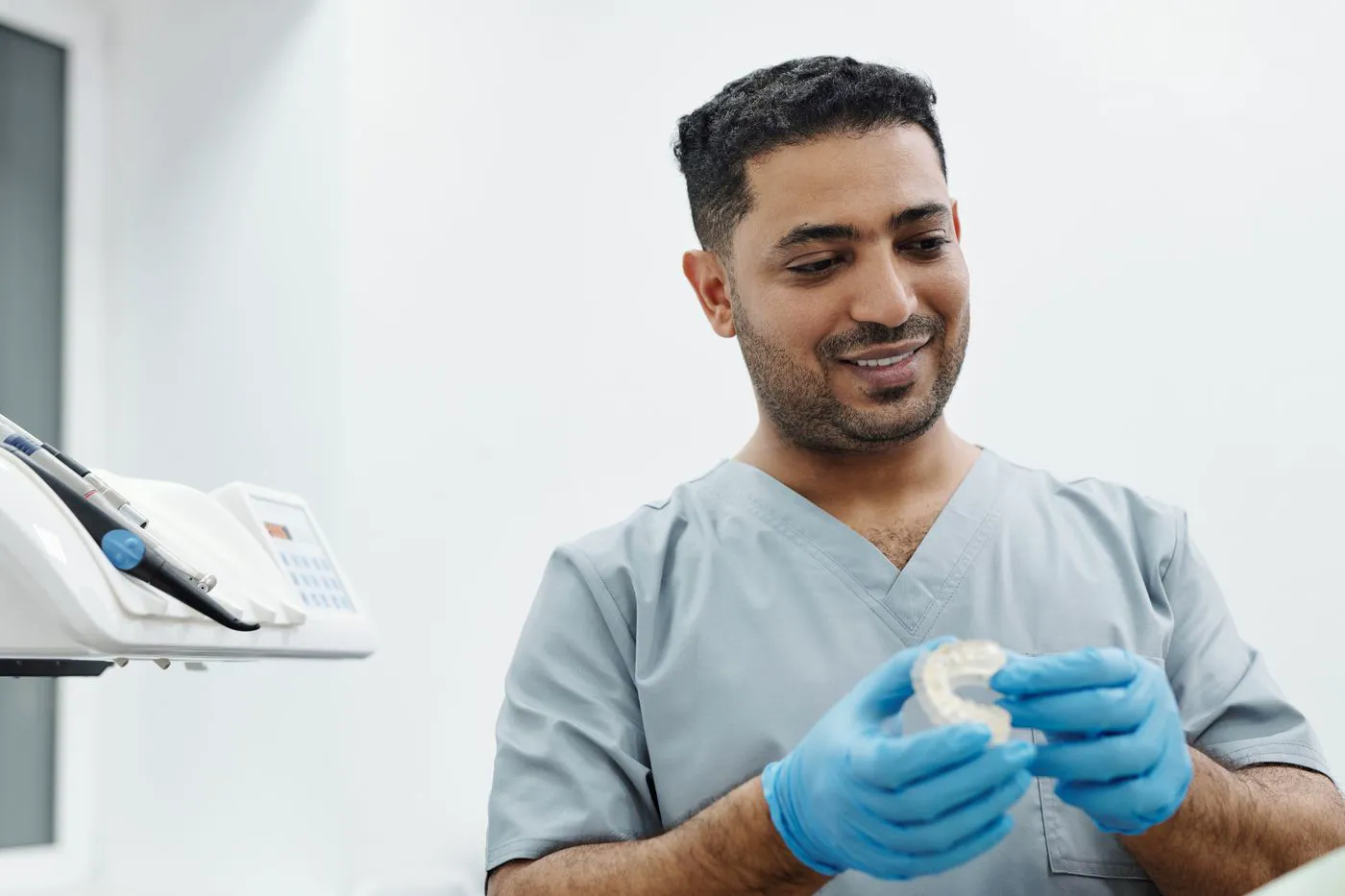 Dr. Arjun Mehta holding a dental model