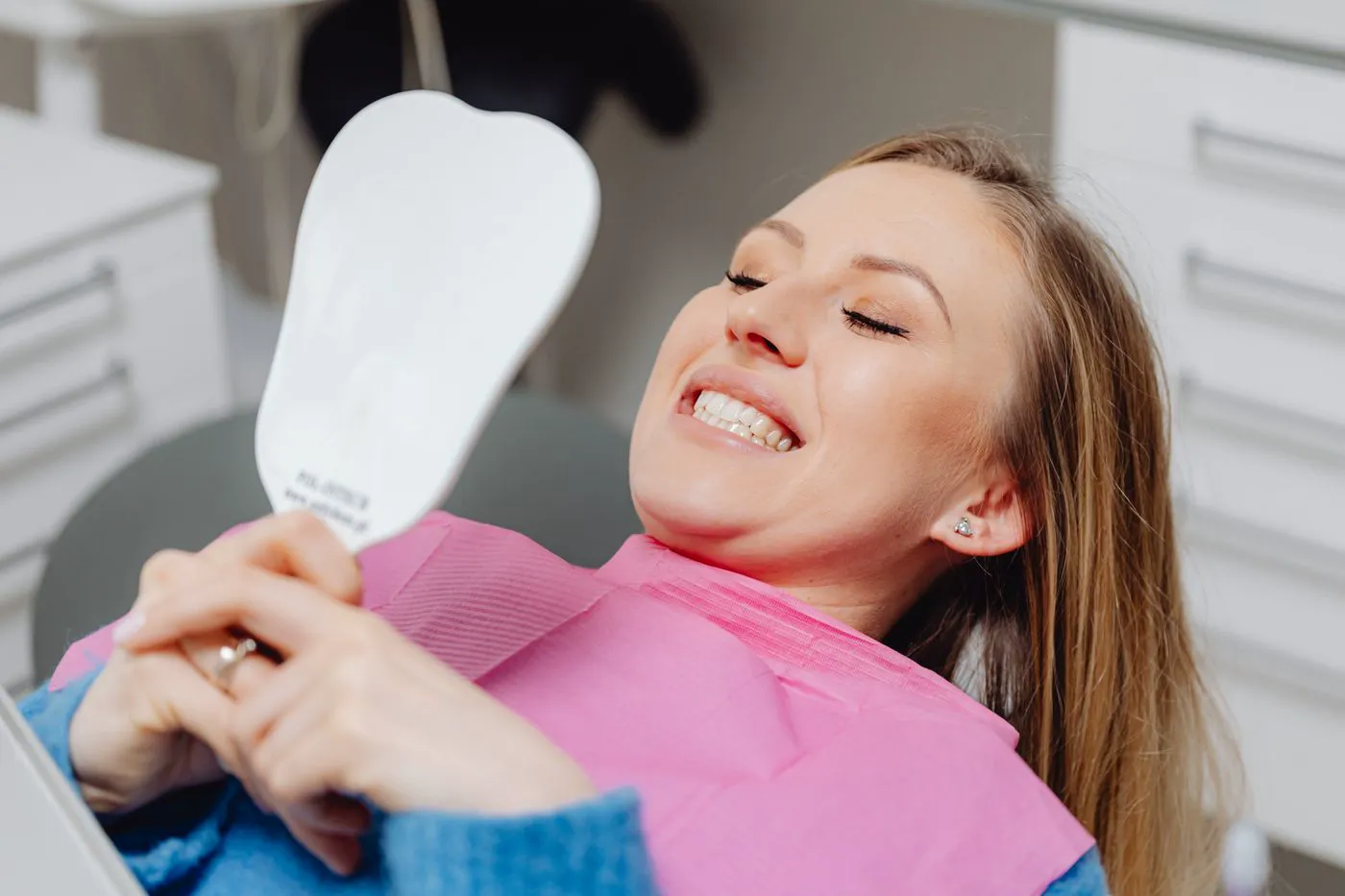 A patient checking her new smile in a mirror