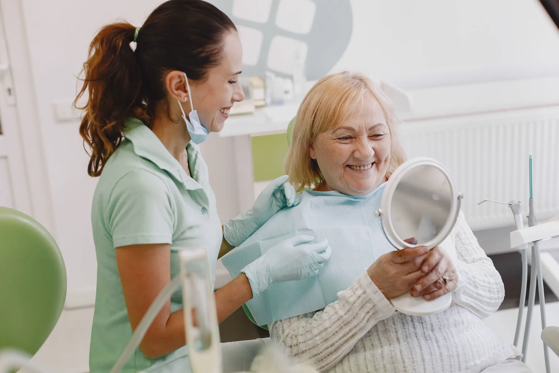 A dentist and her patient smiling into a hand mirror